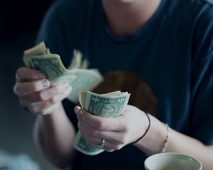 Woman counting the money she has wasted with her ineffective habits